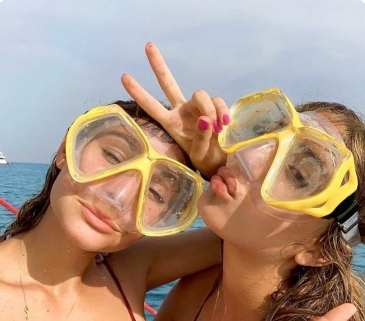 two girls wearing goggles and making the peace sign