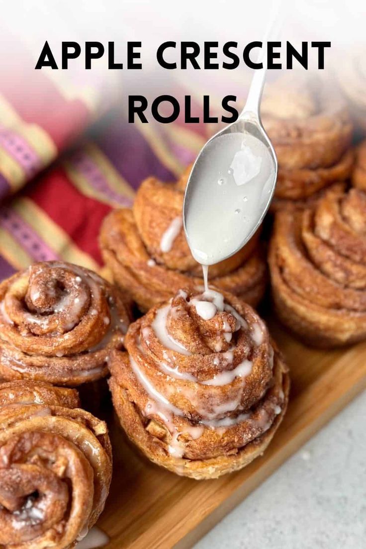 apple crescent rolls with icing being drizzled over them on a wooden platter