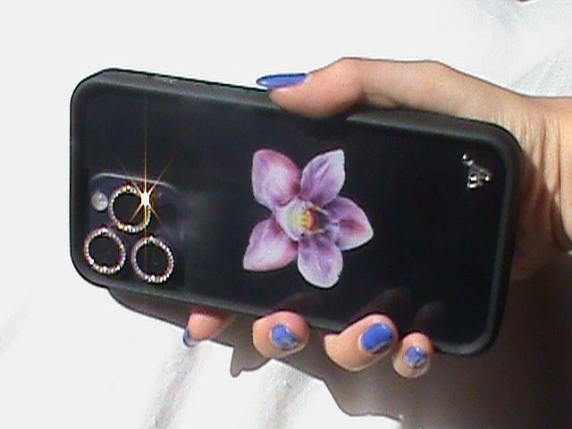 a woman's hand holding up a cell phone with an image of a flower on it