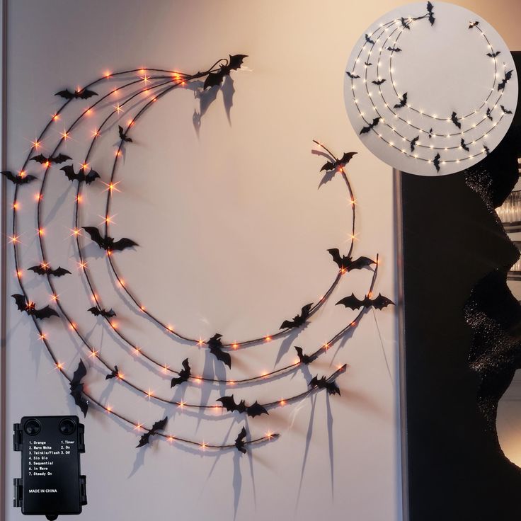 a clock with bats on it is hanging from the wall next to a string of lights