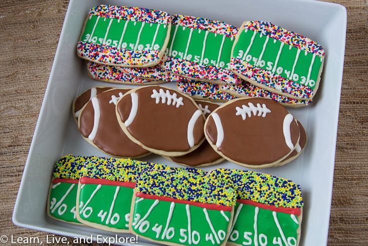 decorated cookies in a tray with footballs and sprinkles on the side