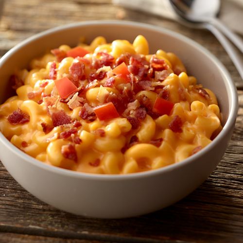 a white bowl filled with macaroni and cheese on top of a wooden table