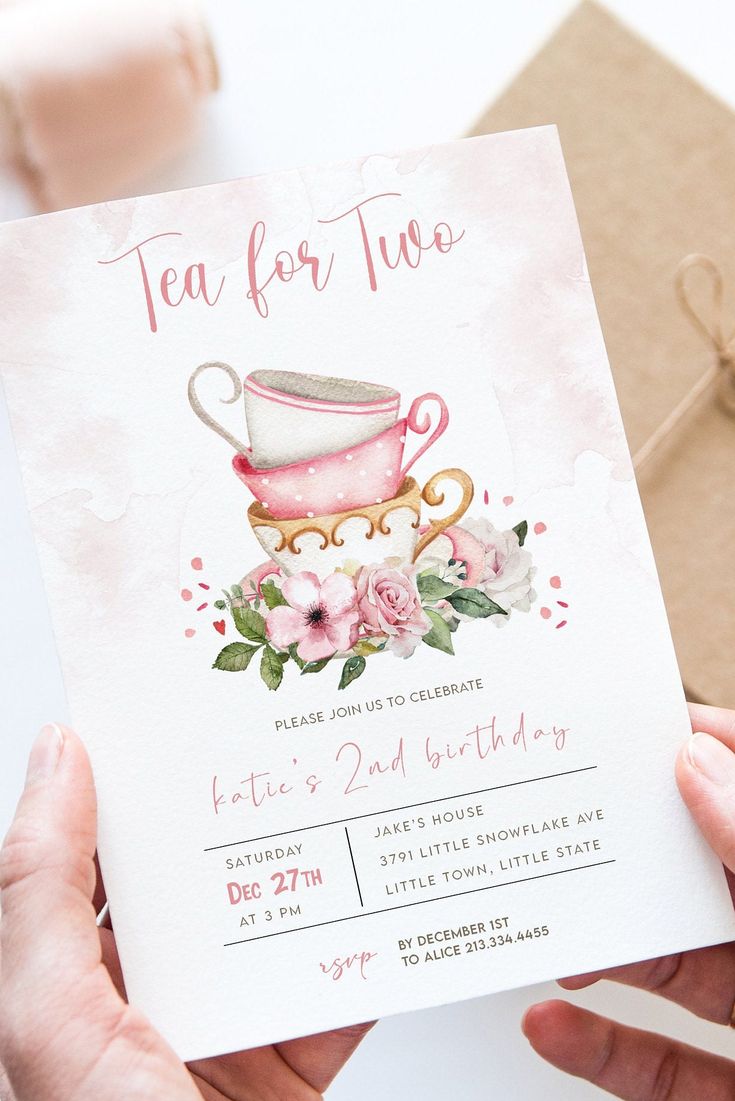 a woman holding up a card with a tea cup on it and flowers in the middle