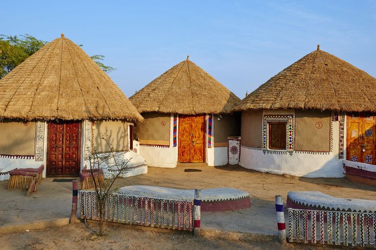 three thatched huts with benches in front of them