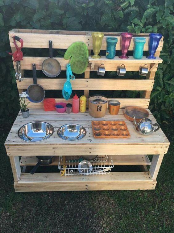 an outdoor kitchen made out of pallets with pots and pans on the shelves