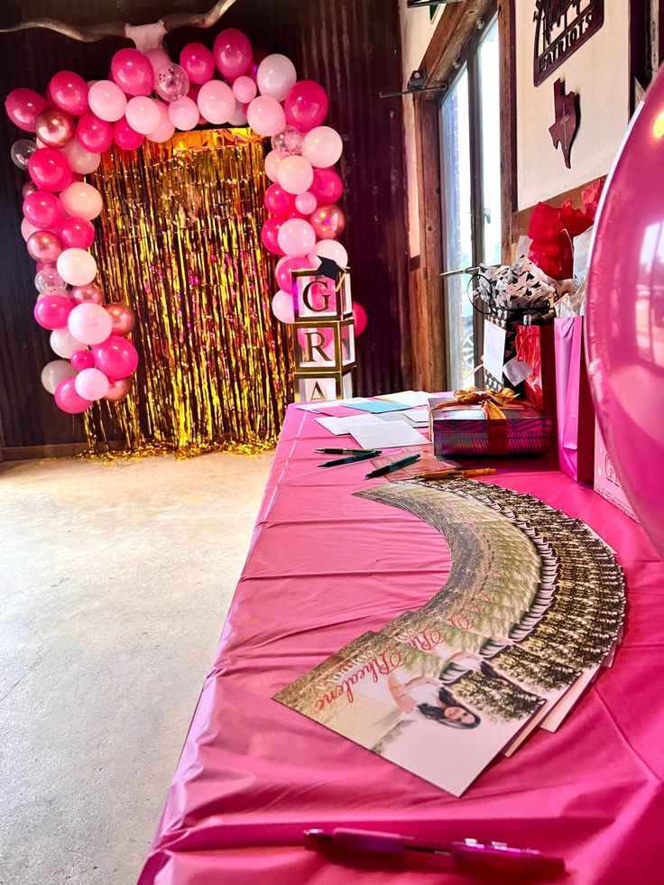 a pink table with balloons and pictures on it