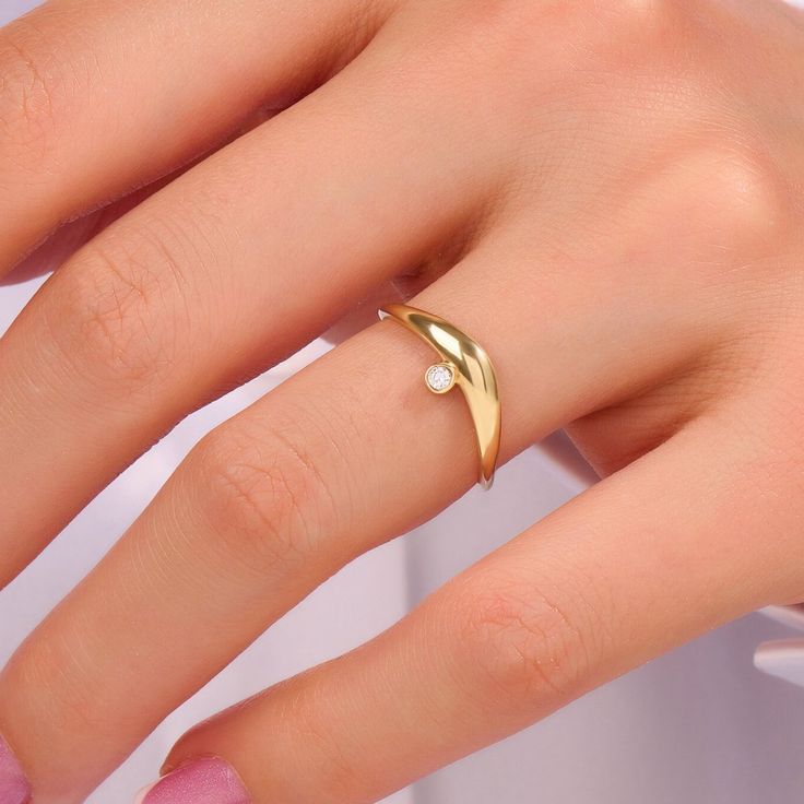 a woman's hand wearing a gold ring with a diamond on it and a pearl in the middle