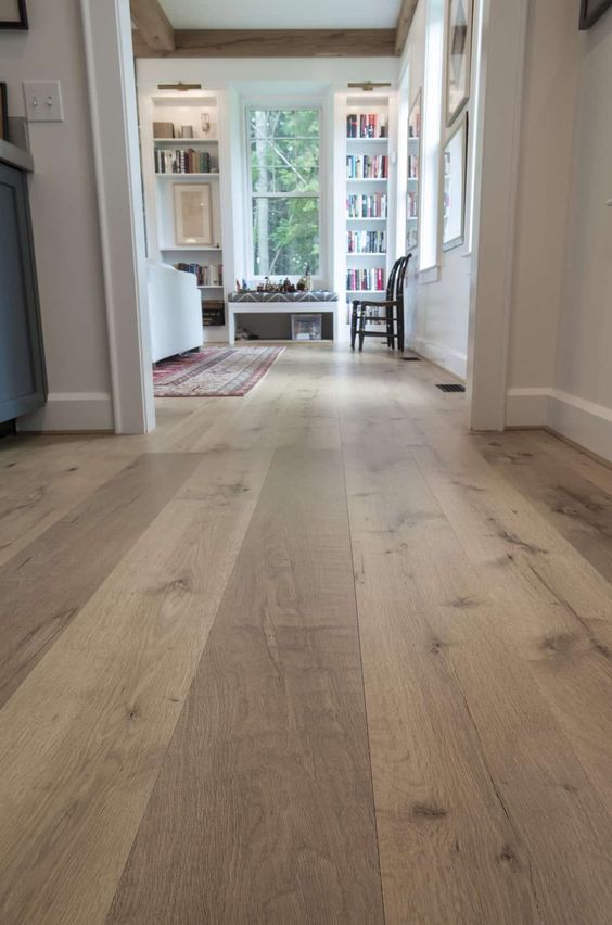 an empty hallway with wood floors and white walls, leading to a living room area