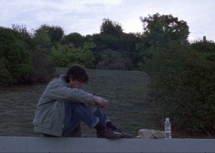 a man sitting on top of a cement wall