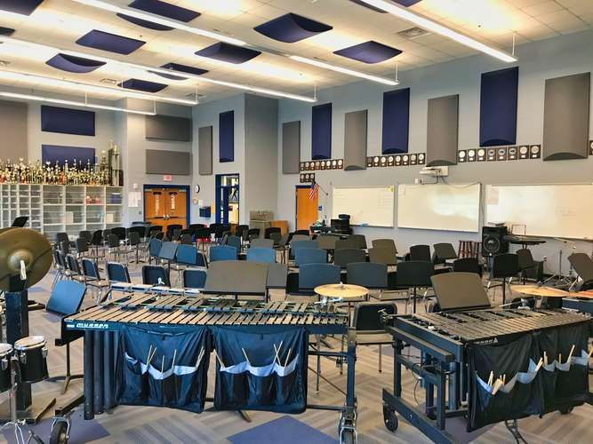 an empty classroom with blue chairs and desks