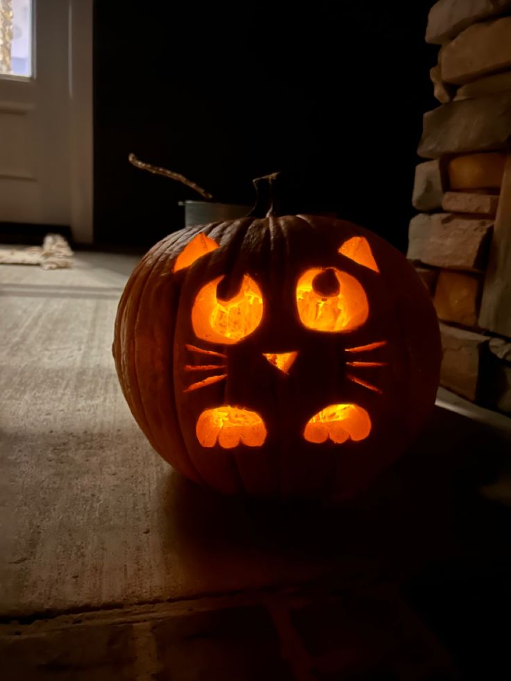 a cat pumpkin carved to look like it has glowing eyes