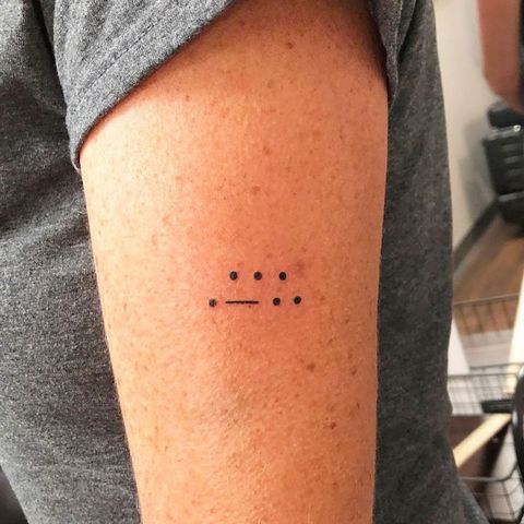 a person with a tattoo on their arm that has four dots in the middle of it