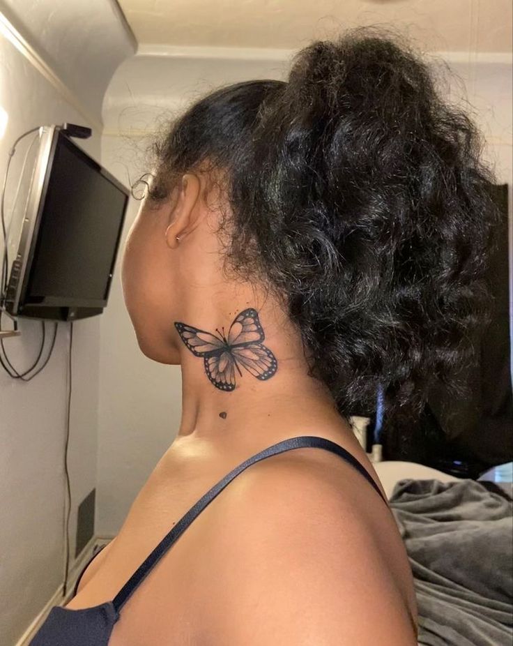 the back of a woman's head with a butterfly tattoo on her left side