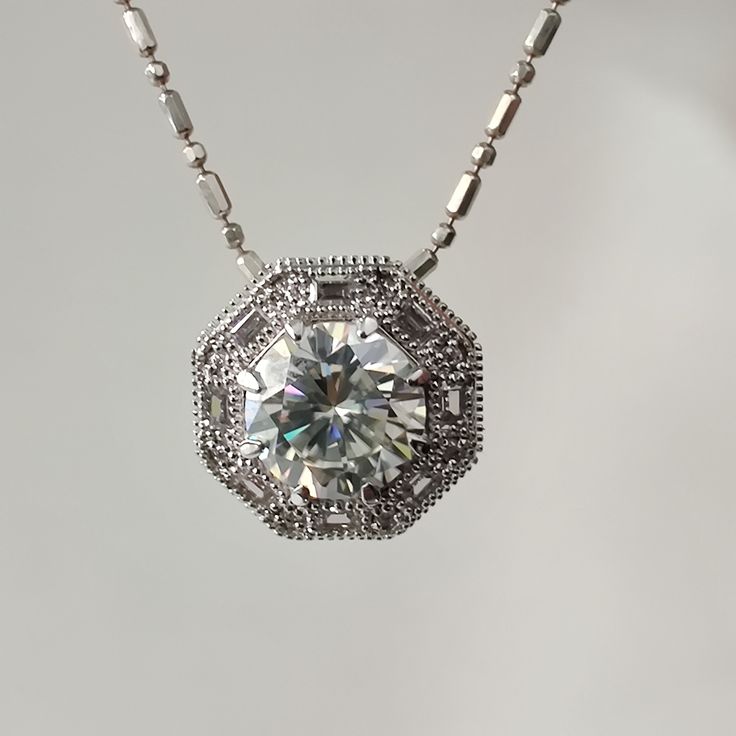 This exquisite pendant features a stunning 2.00-carat round white Moissanite gemstone at its center, brilliantly cut to sparkle and captivate. The vintage octagon-shaped halo design surrounding the central stone adds a touch of timeless elegance and sophistication. Crafted in 925 sterling silver, this classic and elegant drop pendant showcases intricate filigree work, enhancing its beauty and charm. Perfect for any occasion, this women's pendant is a dazzling addition to any jewelry collection. 2.00 Ct Round White Moissanite pendant, Vintage Octagon Shape Halo Design pendant, Classic Elegant Drop 925 silver Womens Filigree Pendant ❤Custom Order Always Welcome❤    Note: Chain is not included only pendent will be shipped  𝗦𝗧𝗢𝗡𝗘 𝗗𝗘𝗧𝗔𝗜𝗟𝗦 Gem Type: Moissanite Center Stone: Moissanit Formal Moissanite Diamond Necklace With Round Pendant, Diamond White Jewelry With Center Stone Round Pendant, Diamond White Round Pendant Jewelry With Center Stone, Formal Moissanite Solitaire Necklace With Round Pendant, Formal Solitaire Moissanite Necklace With Round Pendant, Anniversary Necklace With Round Center Stone, Lab Grown Diamond Pendant Necklace, Dazzling Diamond Cut Solitaire Pendant Necklace, Moissanite Pendant Necklace With Halo Setting