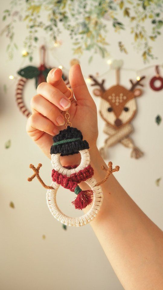 a hand holding onto a christmas ornament with reindeer decorations on the wall behind it