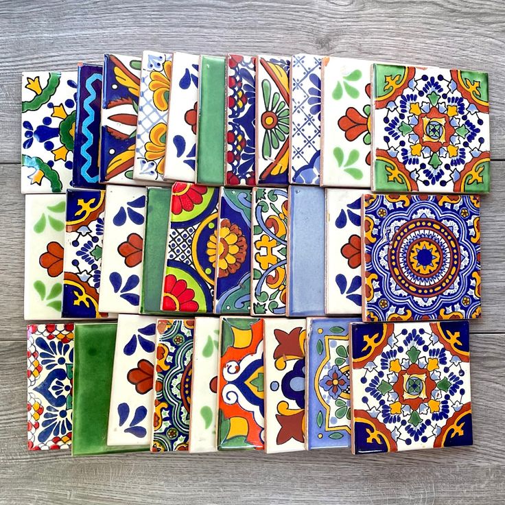 many colorful tiles are arranged on a wooden surface, including one with an intricate design