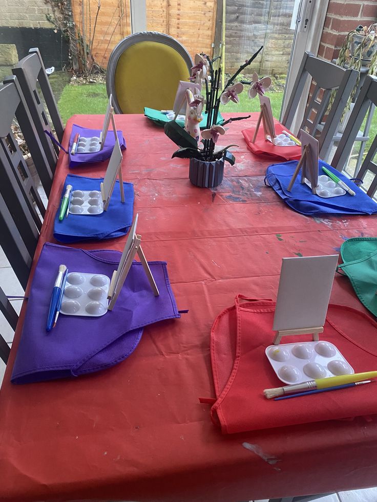 the table is set up with place settings for an art class or birthday party, and it's ready to be eaten