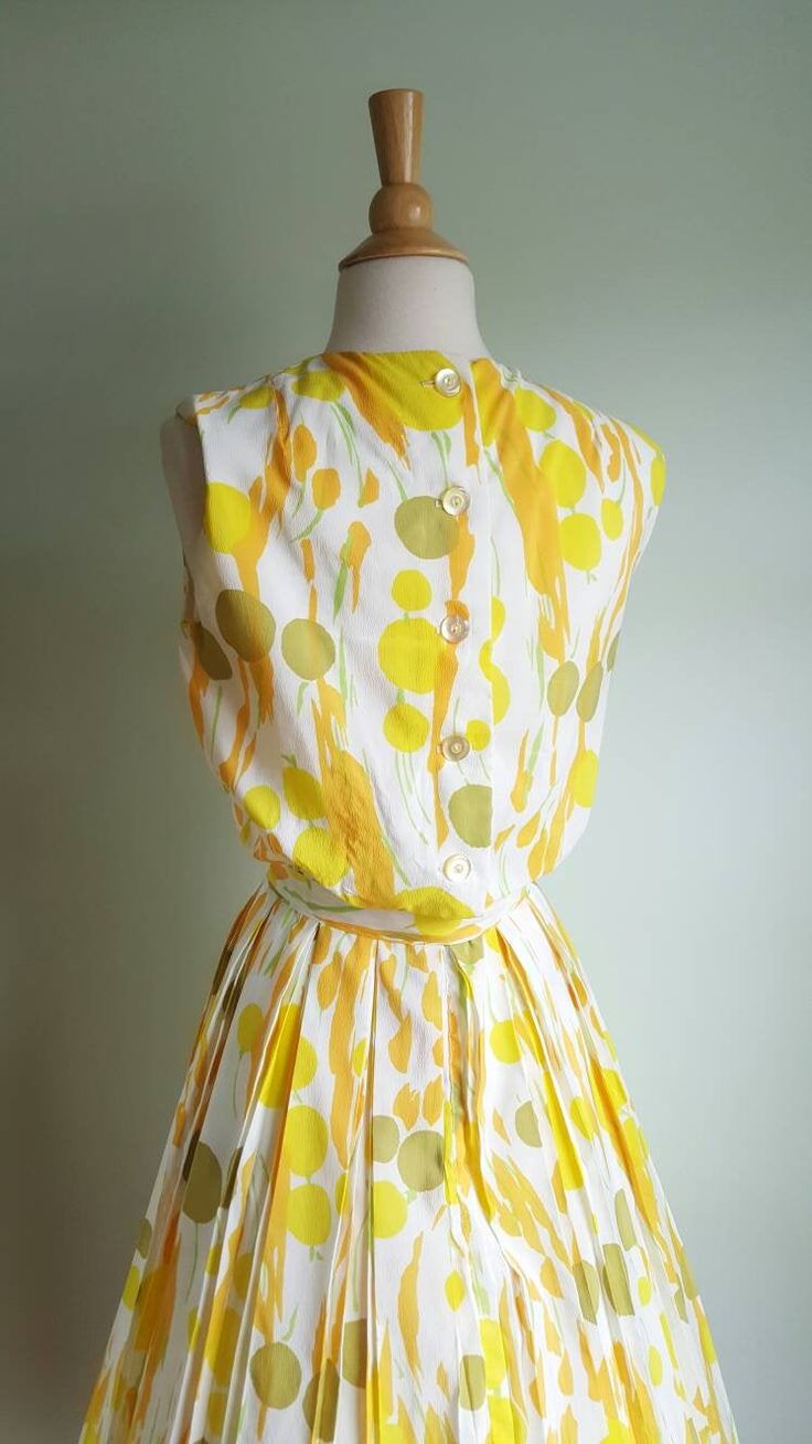 Now that's a cocktail dress! 🍸🍋 This vintage dress looks like an olive martini with a citrus twist, with its fun abstract dot and stem print, bursting with pops of orange, yellow and green on a cream background. It features a blouson-style bodice that buttons in the back; a cinched waist accented by a matching tie sash; and a full, twirly pleated skirt. (Pictured with a crinoline- not included - to demonstrate fullness; its white edge peeks out at the hem.) Bodice is lined; back metal zip at w Summer Garden Party Dress With Box Pleat, Summer Dresses With Box Pleat And Full Skirt, Sleeveless Summer Cocktail Vintage Dress, Retro Spring Dress With Pleated Waist, Spring Retro Dress With Pleated Waist, Retro Sleeveless Cocktail Vintage Dress, Green Retro Dress With Full Skirt, Green Retro Full Skirt Dress, 1950s Style Sleeveless Green Dress