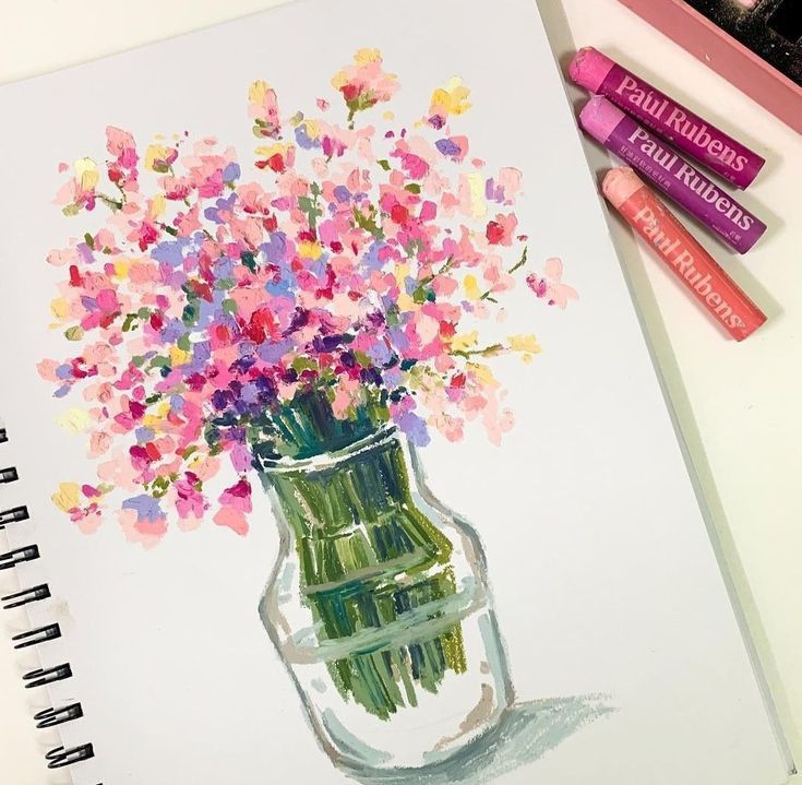 a drawing of flowers in a glass vase with markers on the table next to it