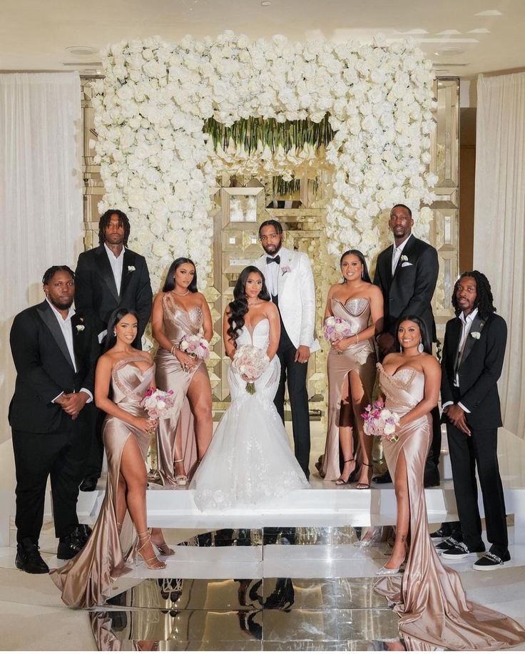 a group of people standing around each other in front of a white and gold backdrop