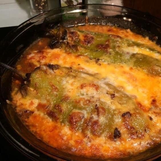 a casserole dish with green peppers and cheese on it sitting on the stove