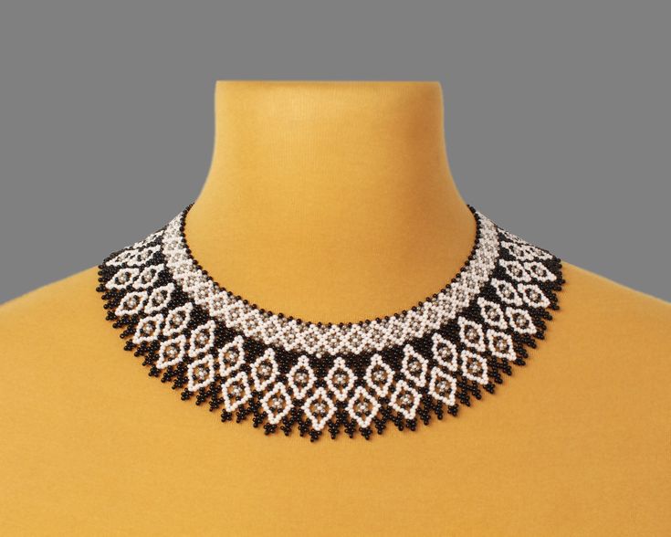 a black and white beaded collar necklace on a mannequin neckline,