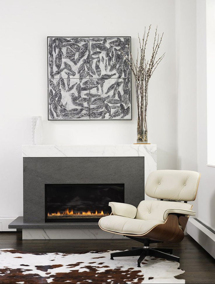 a living room with a fireplace, chair and painting on the wall in it's corner