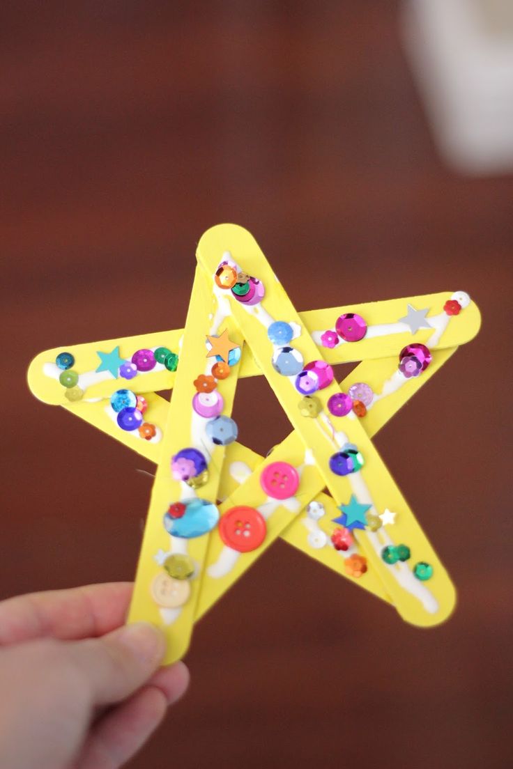 a person holding up a yellow star with buttons on it