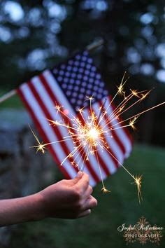 someone holding a sparkler in front of an american flag