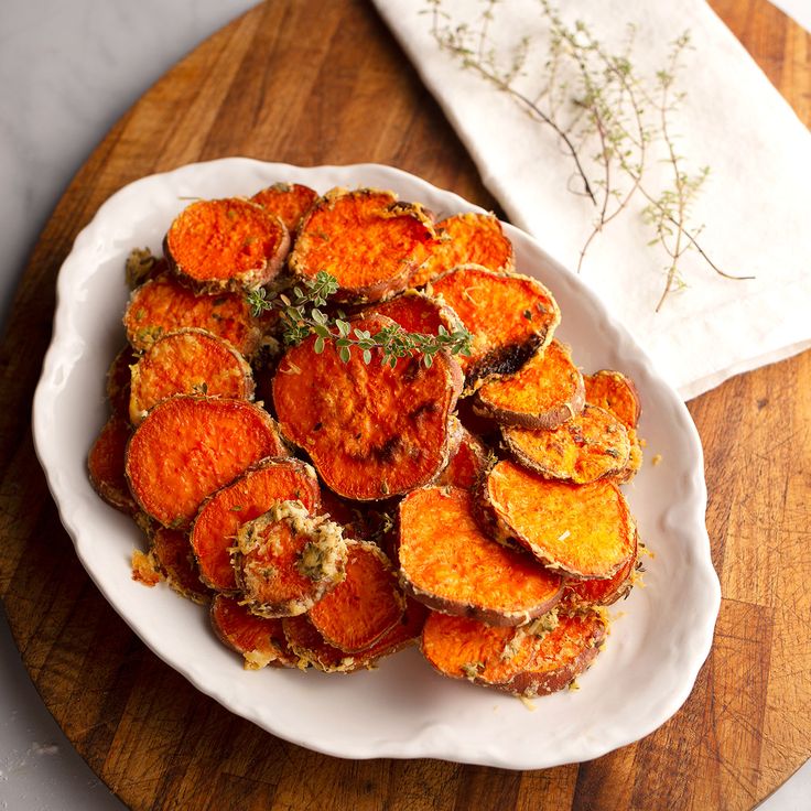 a white plate topped with sweet potato rounds on top of a wooden cutting board next to a napkin