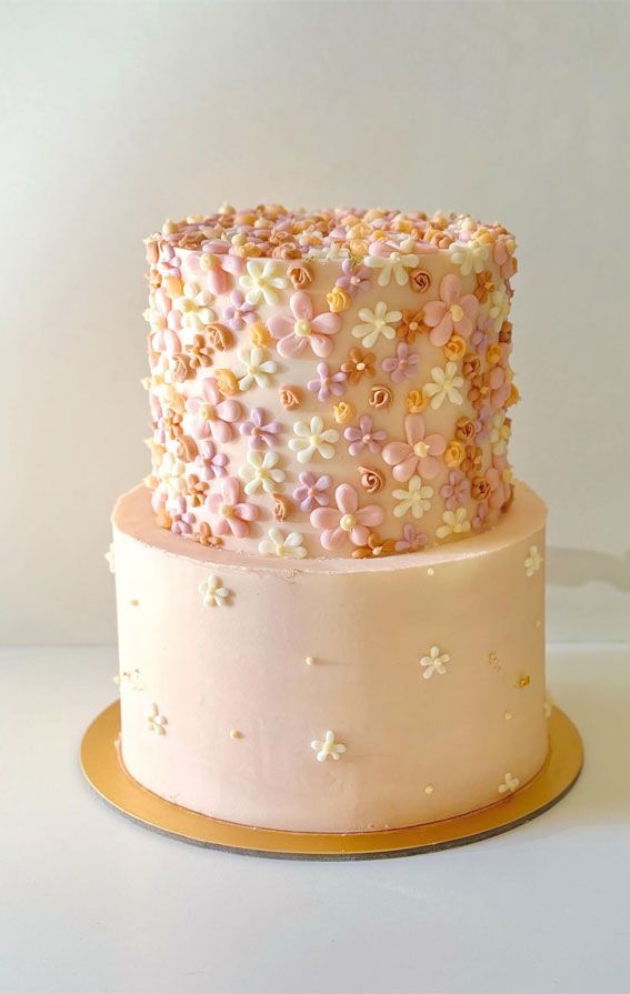 a three tiered cake decorated with flowers and gold sprinkles on a plate