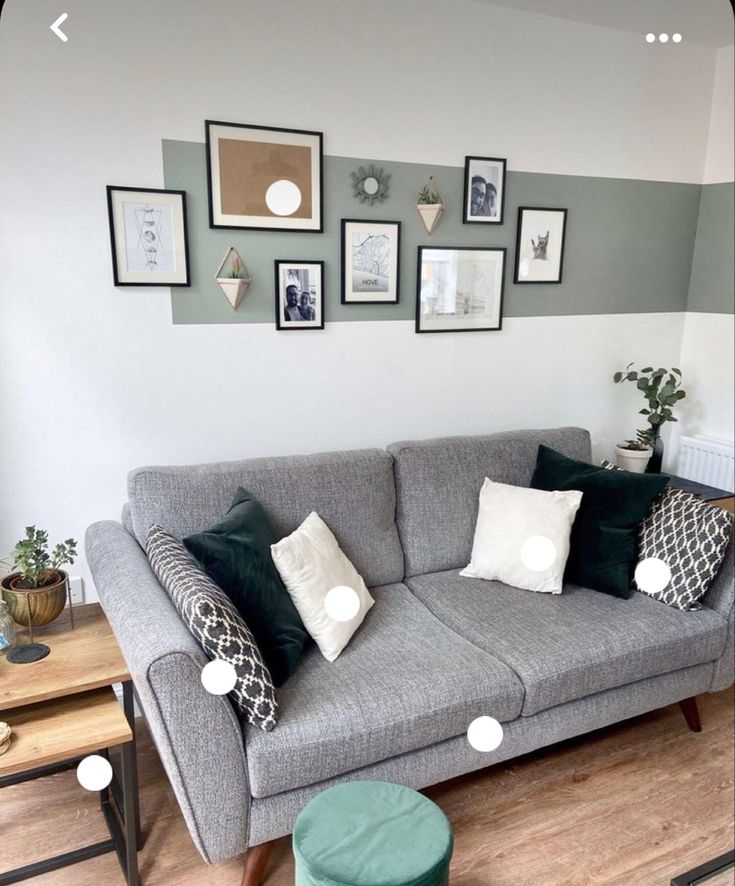 a living room with grey couches and pictures on the wall above them in various frames