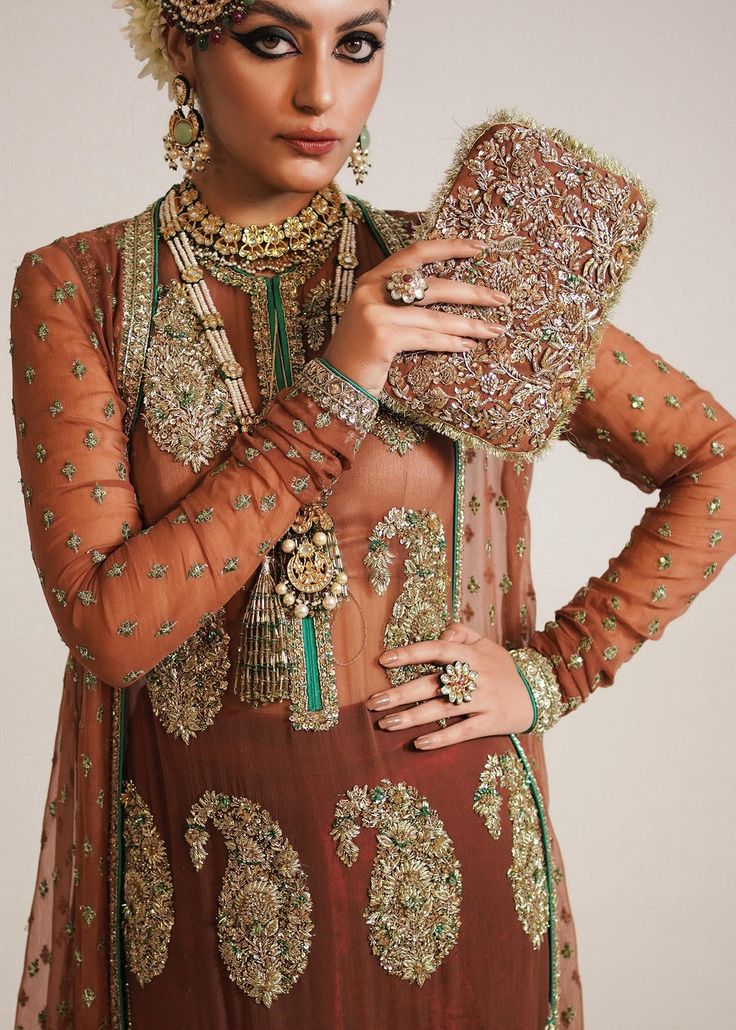 Pakistani Wedding Dress in Brown Sharara and Gown Style is a stunning attire embellished with Naqshi, Dabka, Sequins, Motifs, and Cut-dana. Fast shipping. Elegant Lehenga With Intricate Embroidery For Ceremony, Elegant Ceremony Lehenga With Intricate Embroidery, Elegant Wedding Gown With Resham Embroidery, Hand Embellished Organza Gown For Ceremony, Elegant Formal Gown With Dabka Work, Elegant Gown With Sheer Dupatta For Ceremony, Elegant Hand Embellished Wedding Dress With Traditional Drape, Elegant Wedding Gown With Sheer Dupatta, Bollywood Hand Embellished Formal Gown