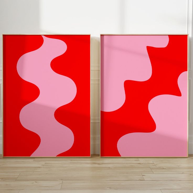 two red and pink paintings sitting on top of a hard wood floor