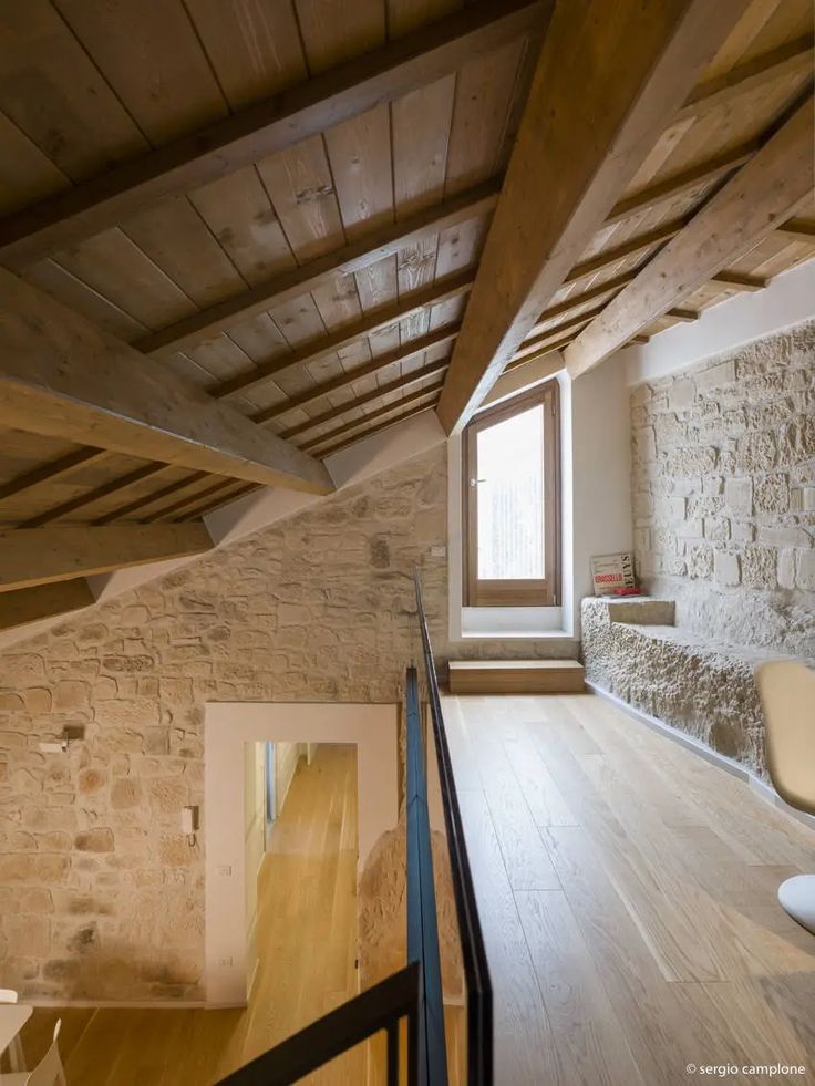 an empty room with wooden floors and stone walls