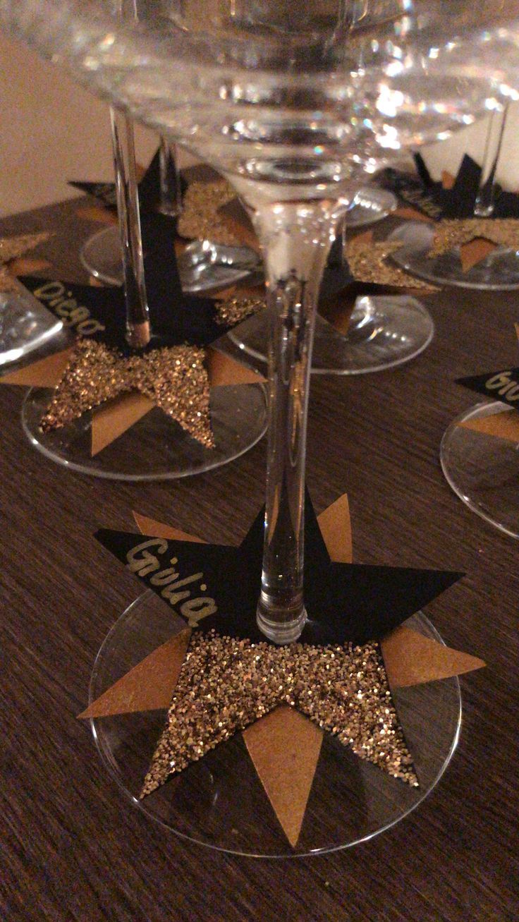 there are wine glasses with gold glitter stars in them on top of a wooden table