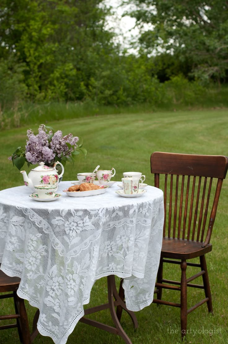 two teacups and a plate on a table in the middle of a field