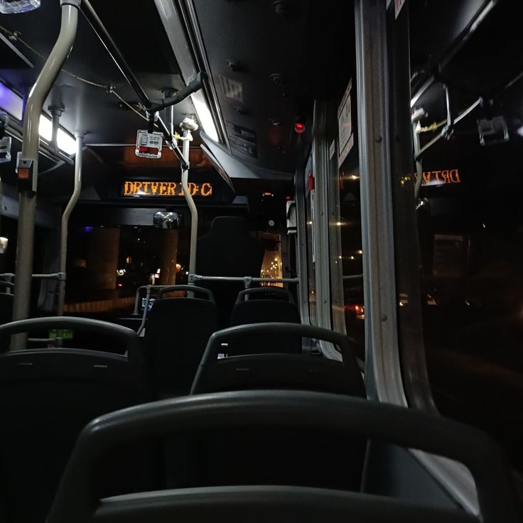 the interior of a public transit bus with its lights on and empty seats at night