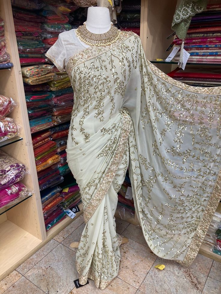 Ivory saree embroidered with zardozi, stone and sequins work saree with unstitched blouse. Fabric: Georgette Ready to Ship! White Blouse Piece With Mirror Work For Festivals, White Semi-stitched Embellished Blouse Piece, Semi-stitched Embellished White Blouse Piece, White Chinon Embroidered Fabric For Wedding, Elegant White Embroidered Saree Fabric, White Embellished Pre-draped Saree For Diwali, Diwali Embellished White Pre-draped Saree, Embellished White Pre-draped Saree For Diwali, Gold Georgette Saree With Intricate Embroidery