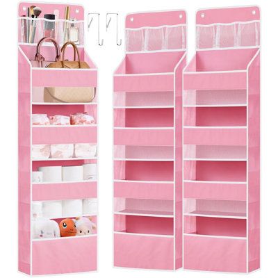 two pink hanging shelves with various items on them and one holding a handbag in it