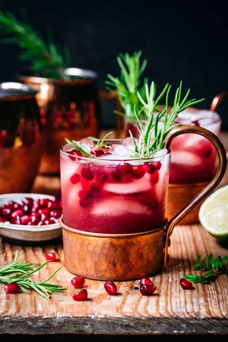 pomegranate and rosemary garnish in copper mugs on wooden table