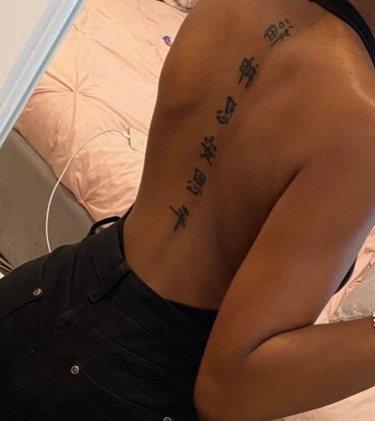 the back of a woman's body with chinese writing tattooed on her lower back