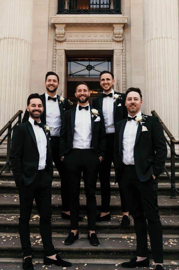 a group of men in tuxedos standing on steps