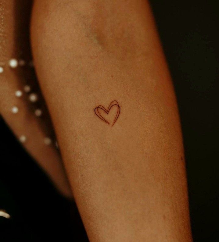 a woman's arm with a small heart tattoo on the left side of her arm