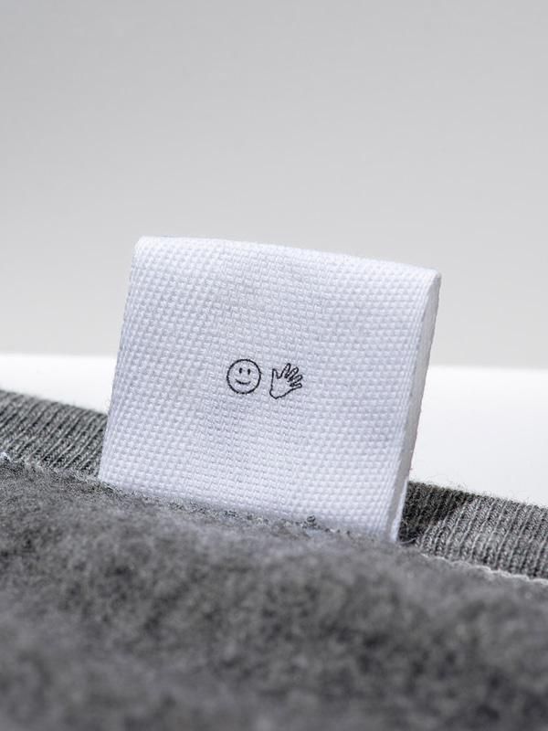 a towel with a smiley face drawn on it sitting on a gray bedding set