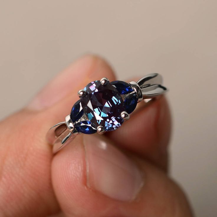 a person holding a ring with a blue stone in it