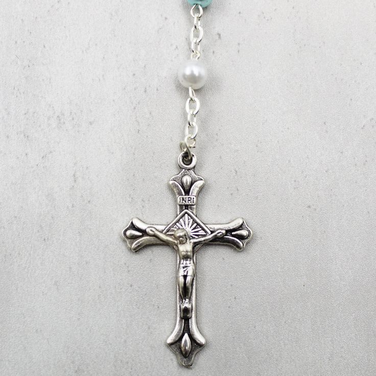 a silver cross with blue beads on a chain