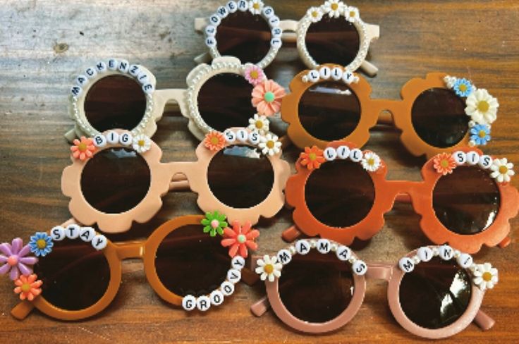 many pairs of sunglasses with flowers on them sitting on a wooden table next to each other