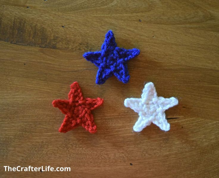 three crocheted stars sitting on top of a wooden table