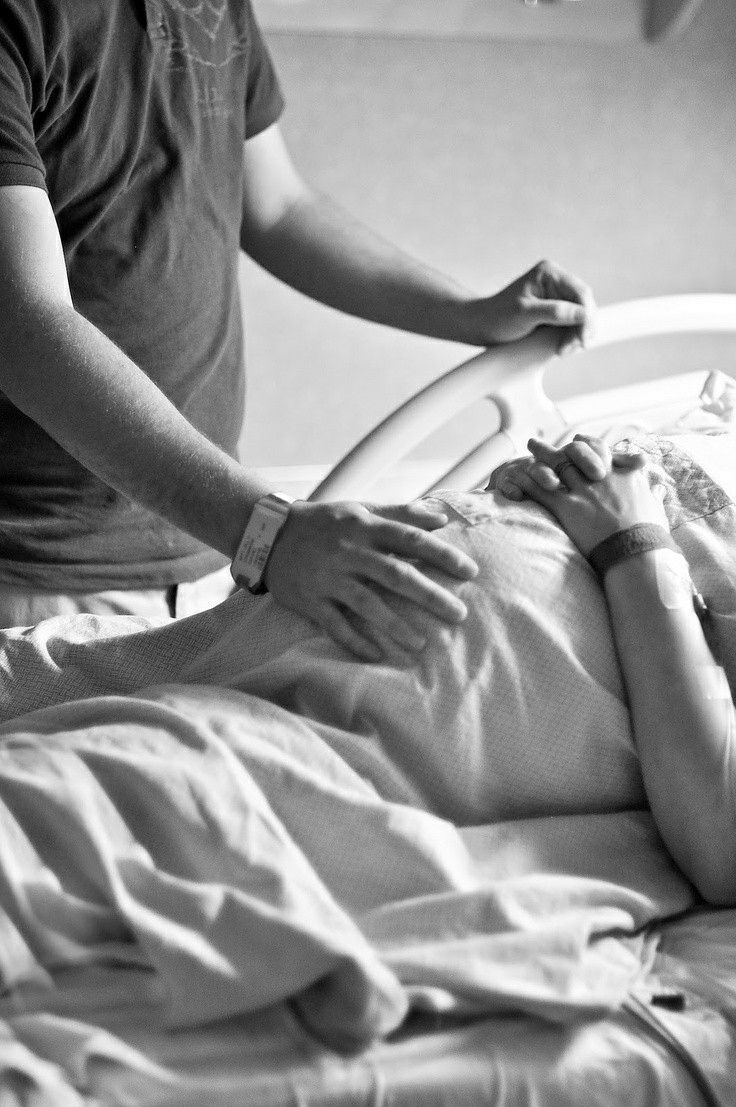 a woman laying in a hospital bed with an iv attached to her arm, being assisted by a nurse